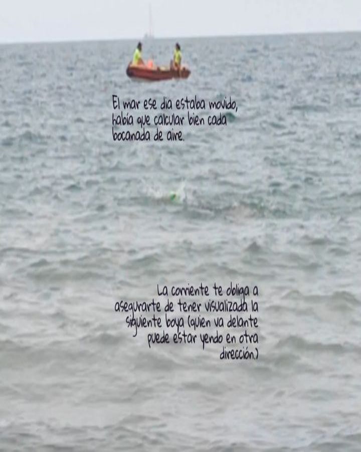 Swimmers in open water with waves and a support boat in the background.